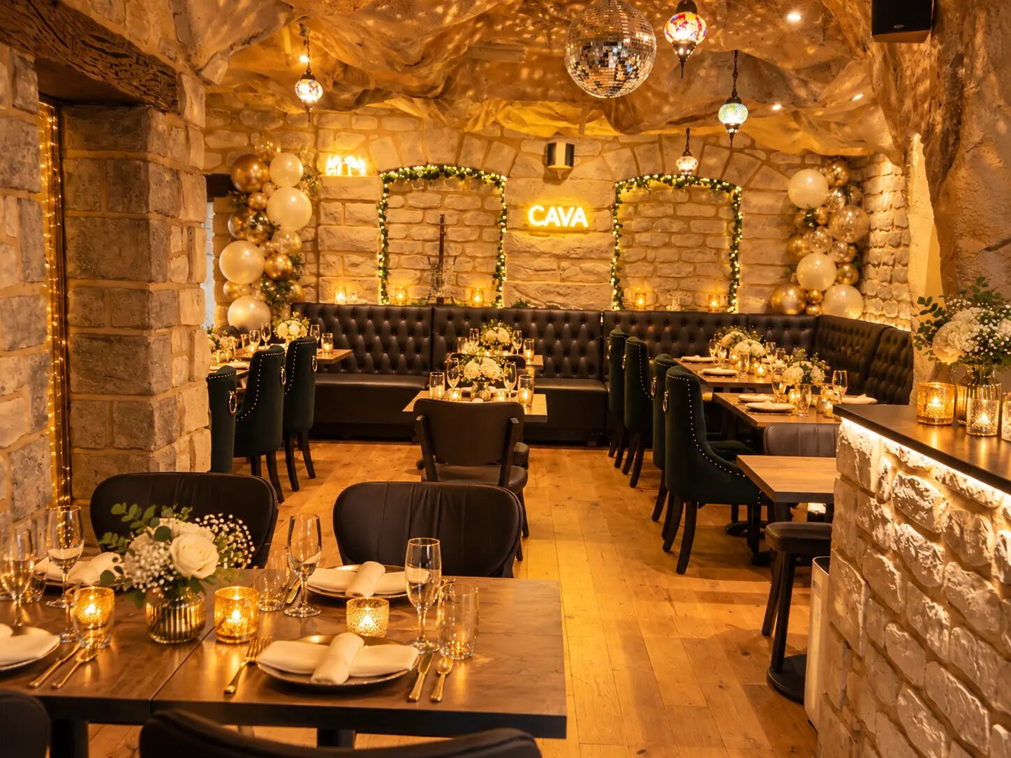 CAVA’s candlelit stone dining room with the glowing CAVA sign